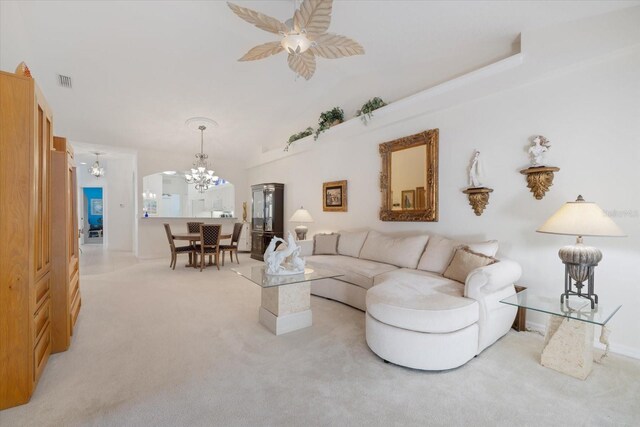 living area with visible vents, light colored carpet, vaulted ceiling, and ceiling fan with notable chandelier