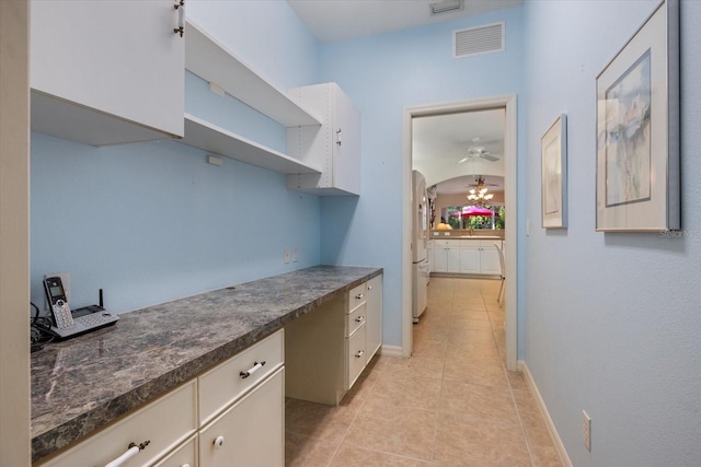 kitchen featuring visible vents, open shelves, dark countertops, freestanding refrigerator, and light tile patterned flooring