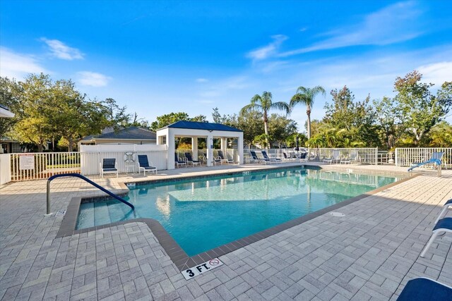 community pool with a patio area and fence