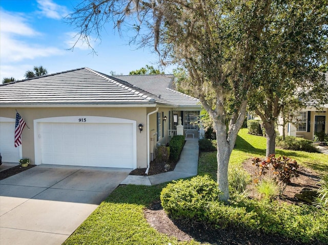 ranch-style home with a front lawn, a tiled roof, concrete driveway, stucco siding, and a garage