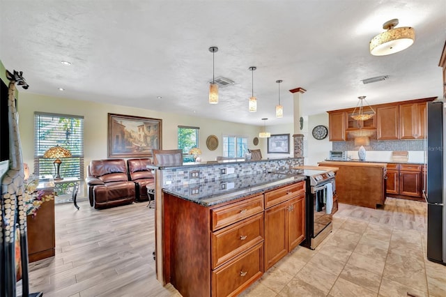 kitchen featuring tasteful backsplash, a kitchen island, open floor plan, stainless steel range with electric cooktop, and dark stone counters