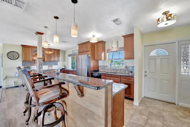 kitchen featuring visible vents, a center island, freestanding refrigerator, and a sink