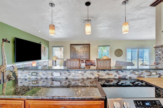 kitchen featuring hanging light fixtures, visible vents, electric stove, and open floor plan