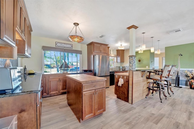 kitchen featuring light wood-style flooring, visible vents, freestanding refrigerator, and a kitchen island