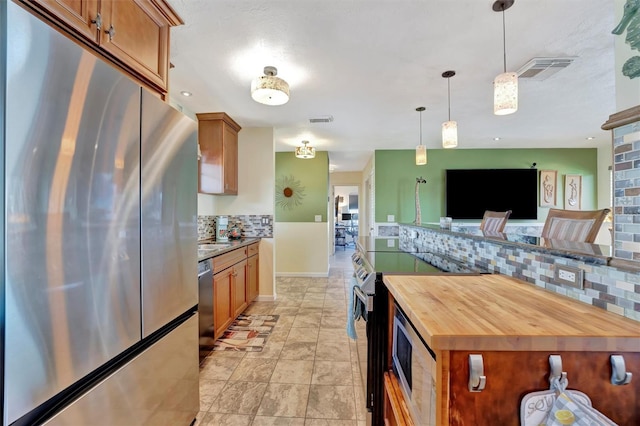 kitchen with visible vents, butcher block counters, decorative backsplash, appliances with stainless steel finishes, and brown cabinetry