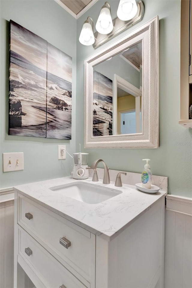 bathroom with a decorative wall, wainscoting, and vanity