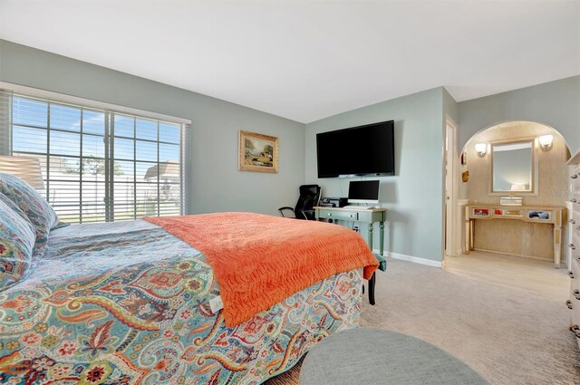 bedroom featuring baseboards, carpet, and arched walkways