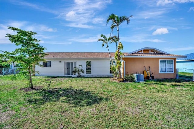 rear view of house featuring central AC unit, a lawn, stucco siding, and fence