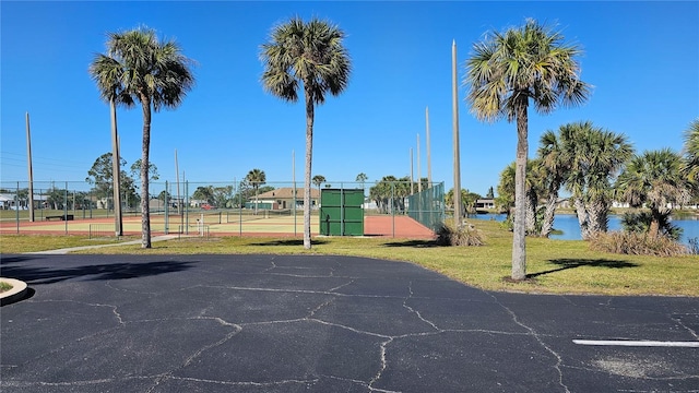 view of basketball court with a tennis court and fence