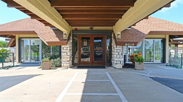 property entrance with french doors, fence, and roof with shingles