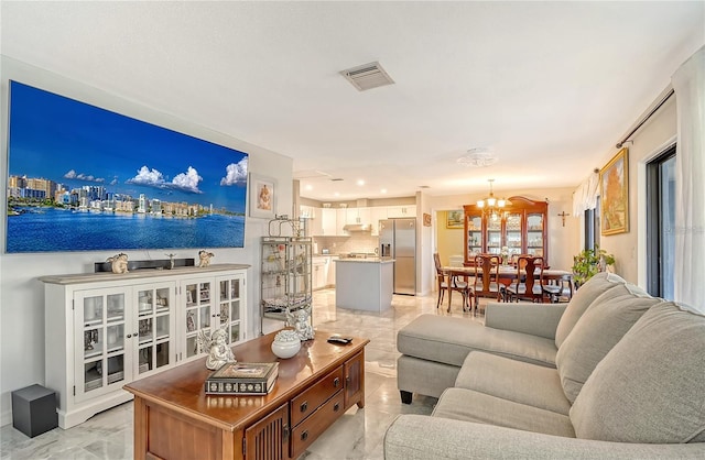 living room featuring a notable chandelier, visible vents, marble finish floor, and baseboards