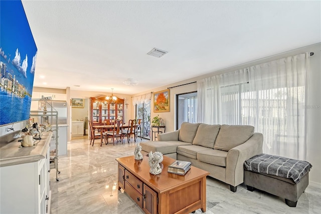 living area featuring visible vents, marble finish floor, and a chandelier