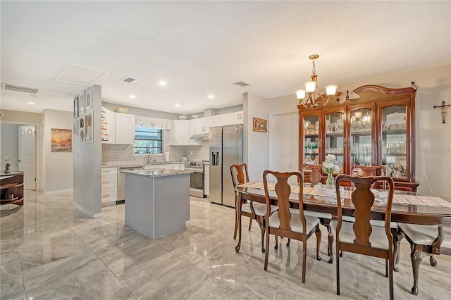 dining space featuring a chandelier, visible vents, and marble finish floor