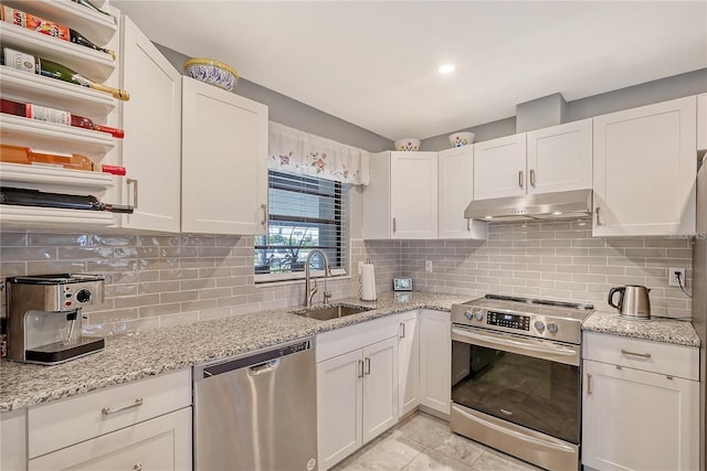 kitchen with a sink, under cabinet range hood, appliances with stainless steel finishes, white cabinetry, and backsplash