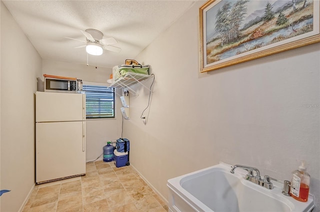 bathroom with a sink, baseboards, a textured ceiling, and a ceiling fan