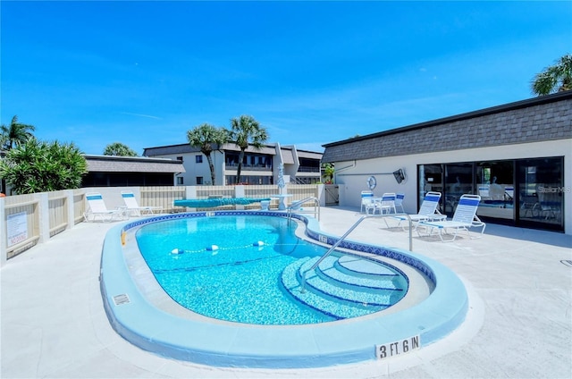 pool with a patio area and fence