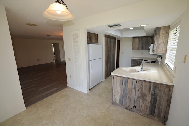 1602 Jim Jim Ct, Venice, FL 34293 - kitchen featuring white appliances, light countertops, dark brown cabinetry, a peninsula, and a raised ceiling