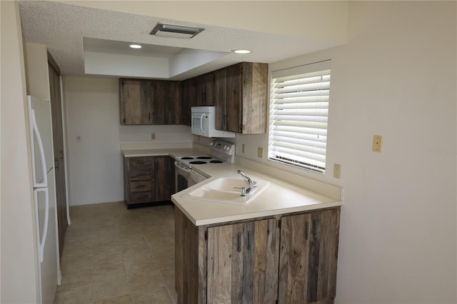 1602 Jim Jim Ct, Venice, FL 34293 - kitchen featuring white appliances, a tray ceiling, light countertops, a peninsula, and a textured ceiling