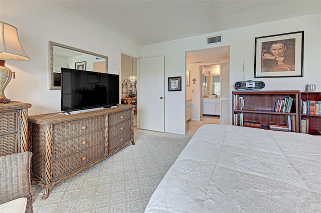 carpeted bedroom with a textured ceiling, visible vents, and connected bathroom