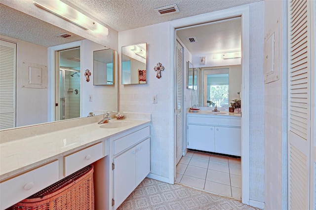 bathroom with a shower stall, visible vents, a closet, and a textured ceiling