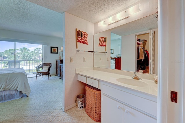 bathroom with a textured ceiling, a spacious closet, and vanity