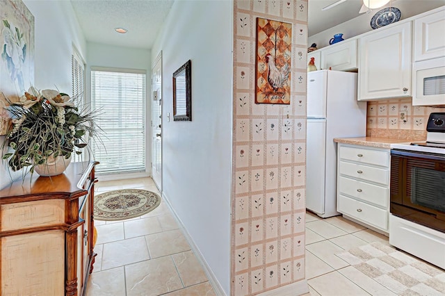 kitchen featuring tasteful backsplash, light countertops, light tile patterned floors, white appliances, and white cabinetry