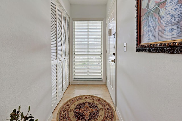 entryway featuring light tile patterned flooring and a textured wall