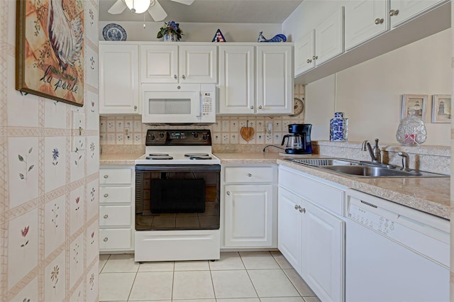 kitchen with a sink, white appliances, light tile patterned flooring, and white cabinets