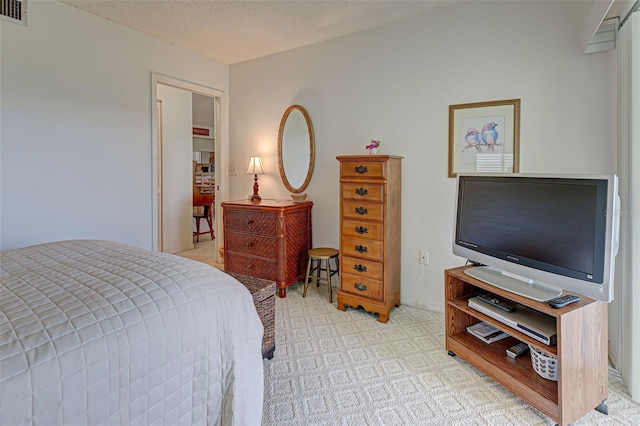 bedroom featuring light colored carpet, visible vents, and a textured ceiling