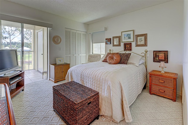 bedroom featuring multiple windows, a textured ceiling, light carpet, and access to exterior