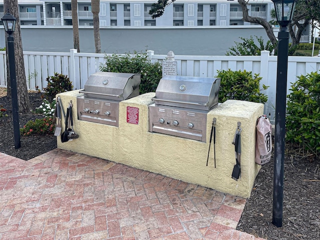 view of patio with a residential view, a grill, an outdoor kitchen, and fence