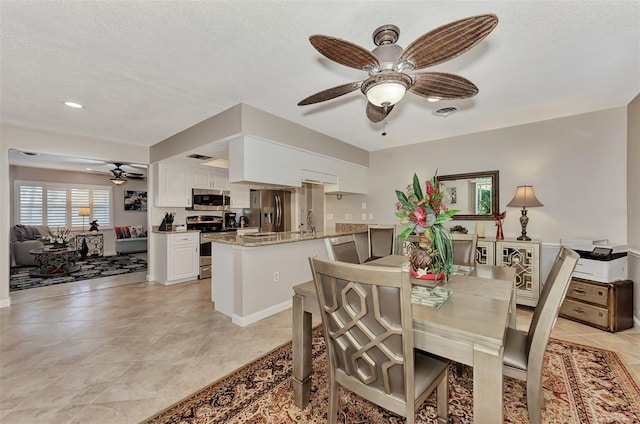 dining area featuring light tile patterned floors, visible vents, a textured ceiling, and ceiling fan