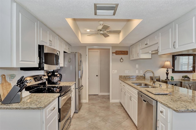 kitchen featuring visible vents, a tray ceiling, a sink, appliances with stainless steel finishes, and white cabinetry