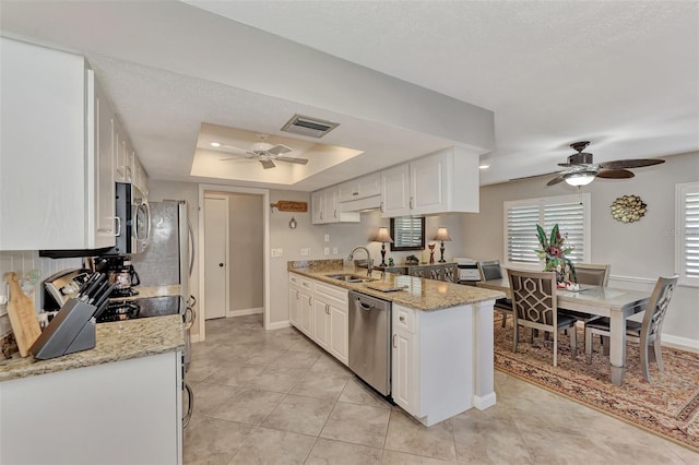 kitchen featuring a ceiling fan, visible vents, a tray ceiling, a sink, and appliances with stainless steel finishes