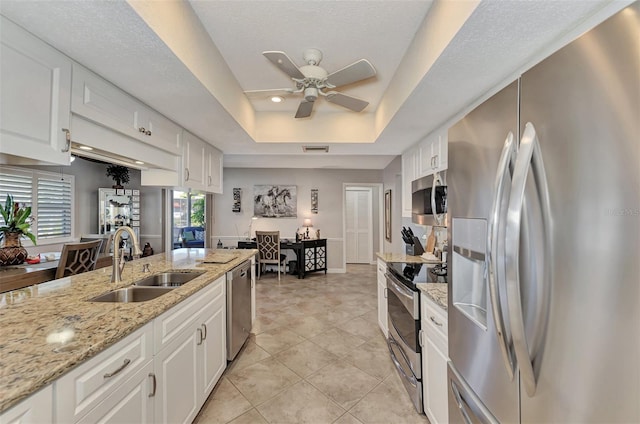 kitchen with a ceiling fan, visible vents, a sink, appliances with stainless steel finishes, and a raised ceiling