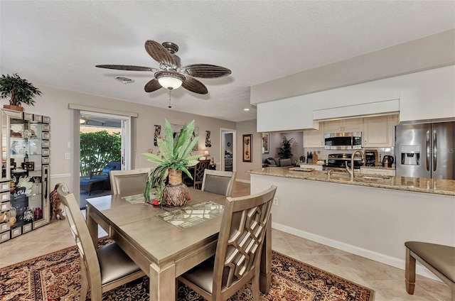 dining room with light tile patterned floors, baseboards, visible vents, ceiling fan, and a textured ceiling