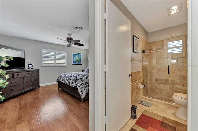 ensuite bathroom featuring a shower stall, toilet, ensuite bathroom, wood finished floors, and a ceiling fan