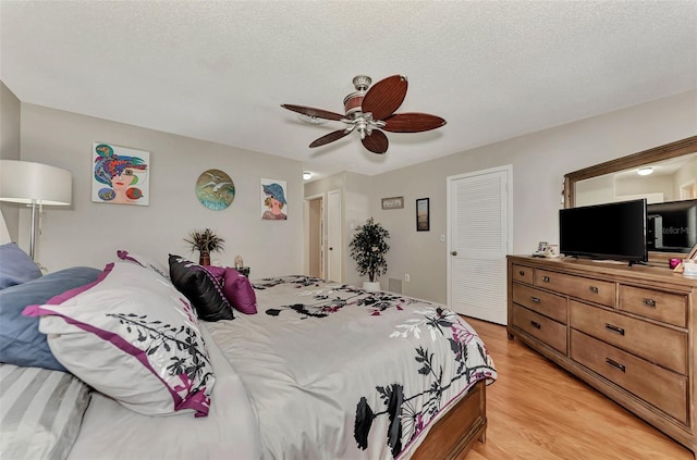 bedroom featuring a closet, ceiling fan, a textured ceiling, and light wood-style floors