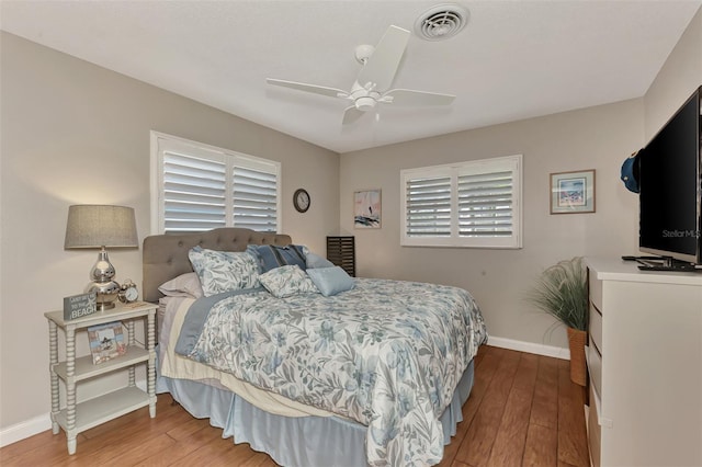 bedroom with ceiling fan, visible vents, baseboards, and hardwood / wood-style floors