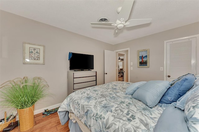 bedroom featuring ceiling fan, wood finished floors, visible vents, and baseboards