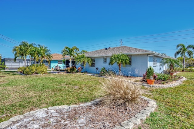 ranch-style home with stucco siding, roof with shingles, and a front lawn