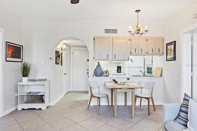 kitchen featuring visible vents, a notable chandelier, backsplash, freestanding refrigerator, and arched walkways