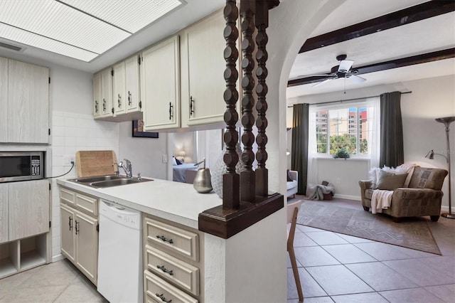 kitchen featuring stainless steel microwave, backsplash, white dishwasher, light tile patterned flooring, and a sink