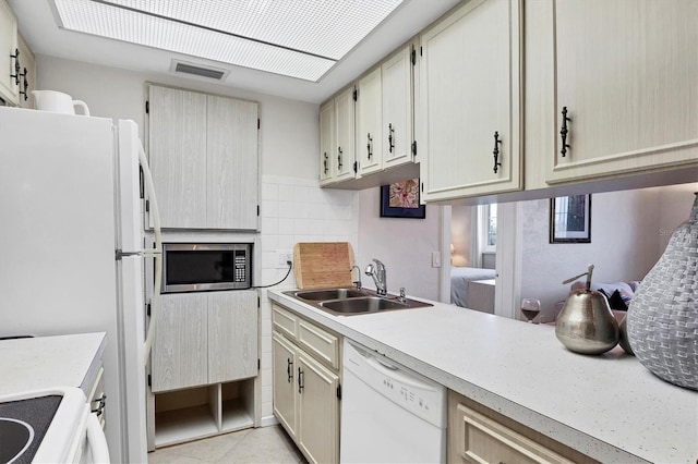 kitchen featuring visible vents, a sink, backsplash, white appliances, and light countertops