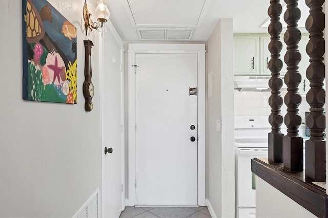 doorway with light tile patterned floors, visible vents, and baseboards