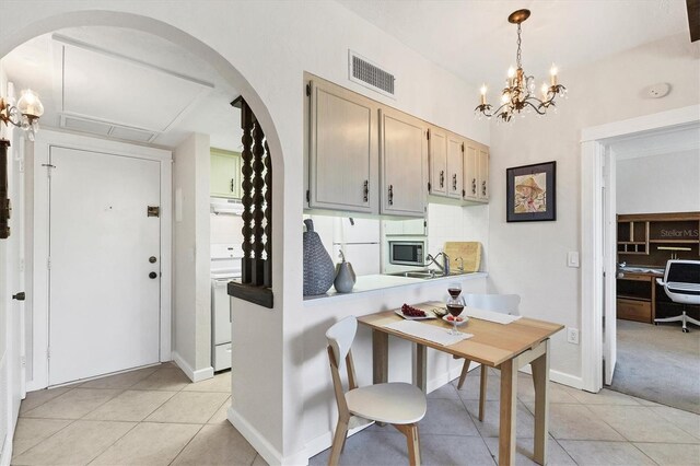 kitchen featuring light tile patterned floors, visible vents, white range with electric cooktop, under cabinet range hood, and a chandelier