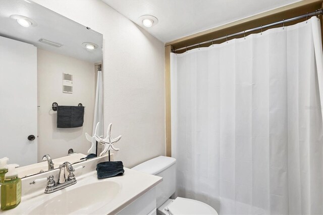 bathroom with visible vents, toilet, vanity, and a shower with curtain