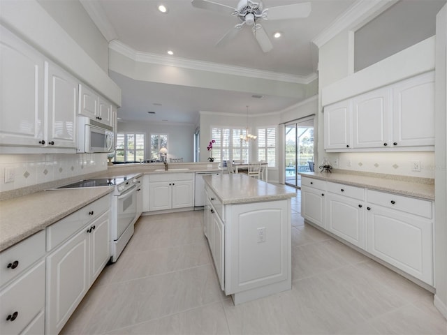 kitchen featuring ceiling fan with notable chandelier, white appliances, crown molding, and a peninsula