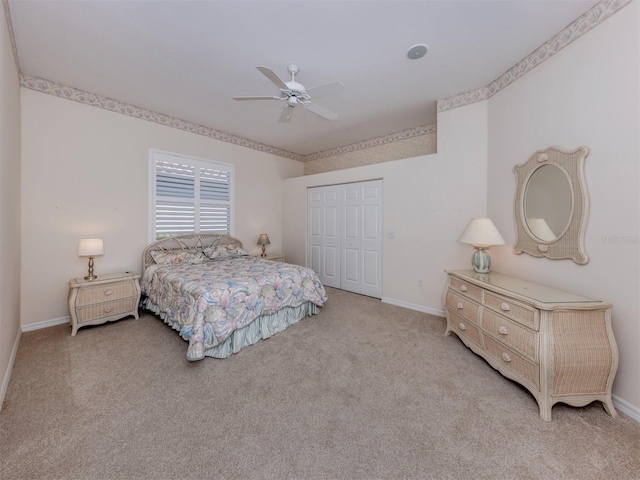 bedroom with a closet, light carpet, baseboards, and ceiling fan