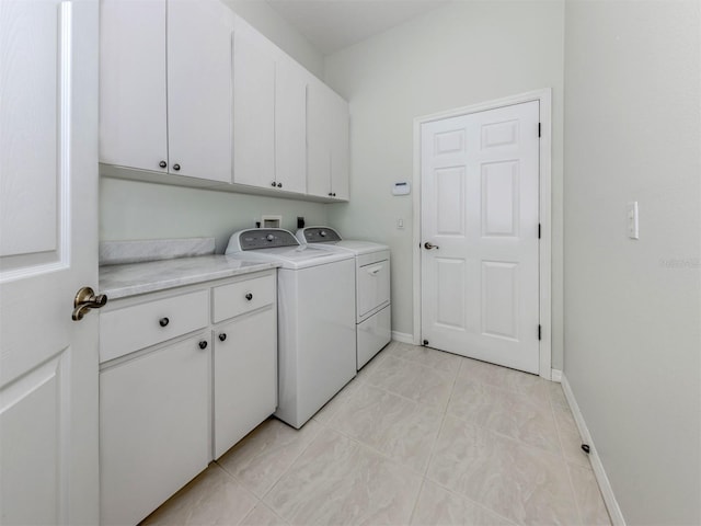 laundry area featuring washing machine and clothes dryer, light tile patterned floors, cabinet space, and baseboards